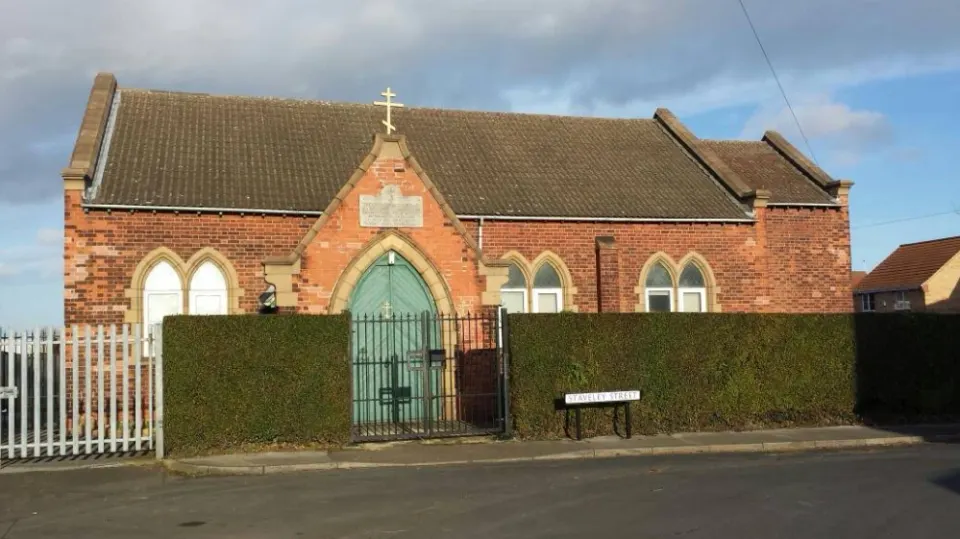 The church from Staveley Street, with its green door and three-bar cross