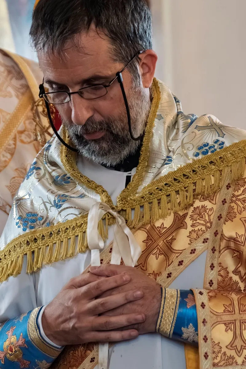 A clergyman of the parish bowed in prayer, hands folded